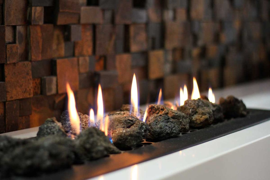 Gas fireplace with lit fire installed on a television set and bottom in small stones
