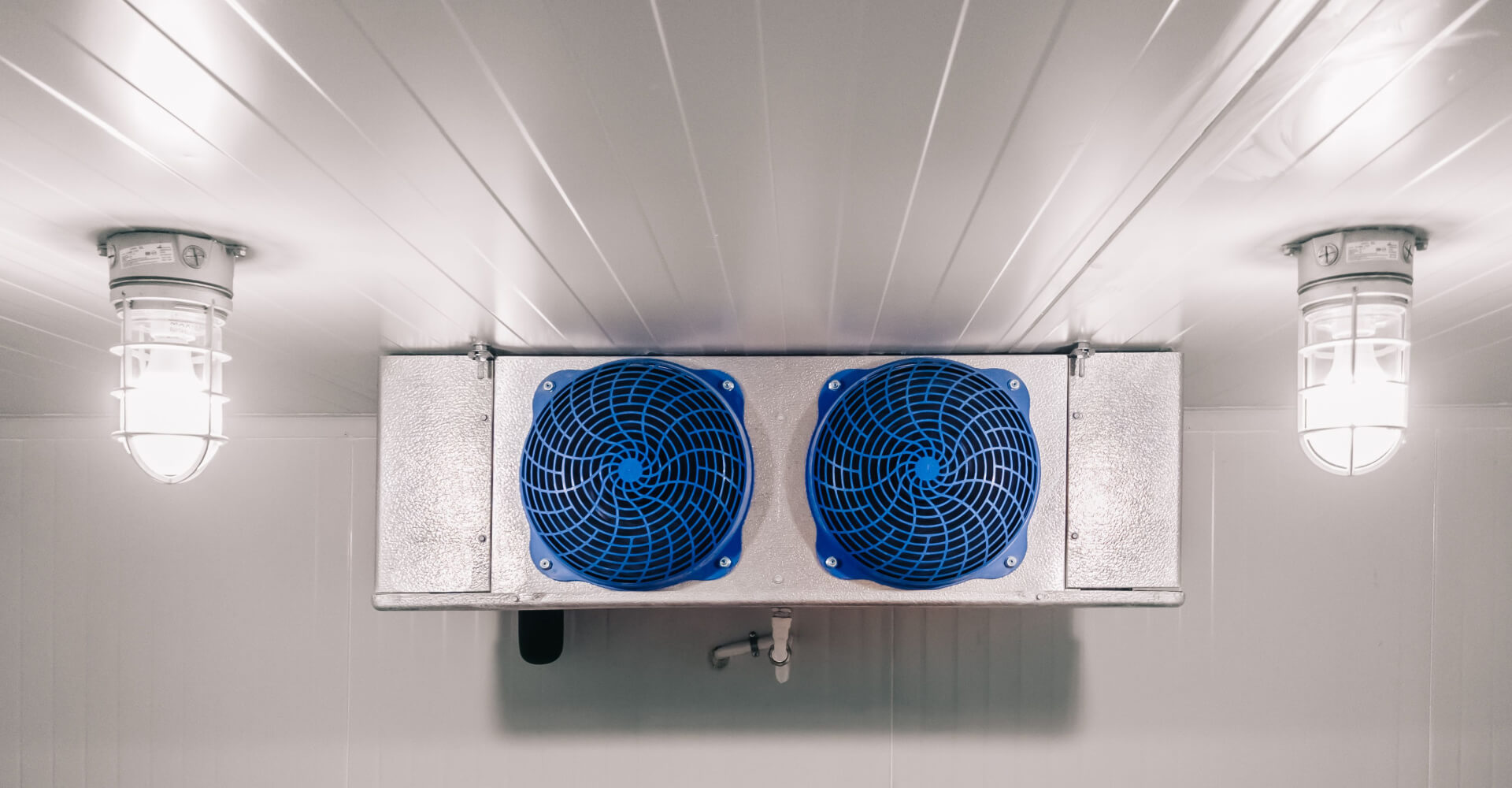 Two fan evaporator air cooler on a cold room with two lights.